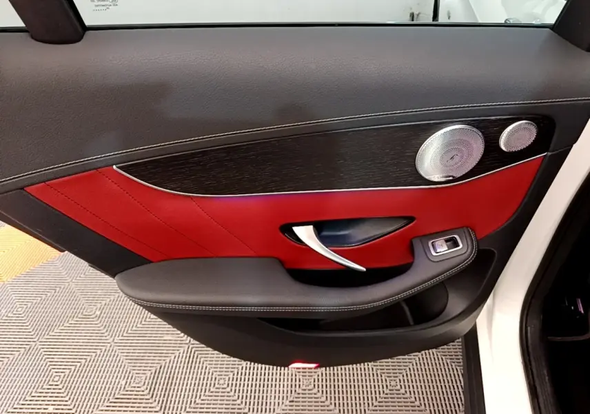 Gros plan sur la porte côté gauche d’un Mercedes GLC 300 e AMG Line blanc, avec intérieur cuir rouge et noir.