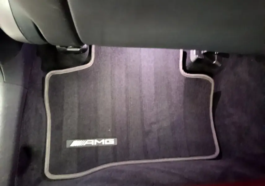 Tapis de sol noir avec logo AMG visible à l'avant droit dans l'habitacle d'un Mercedes GLC Coupé blanc.