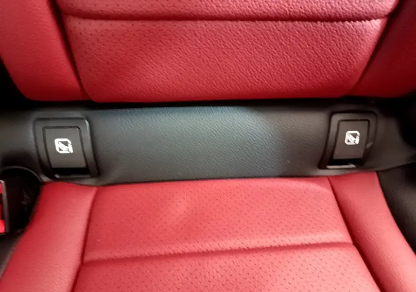 Gros plan sur la banquette arrière rouge avec fixation Isofix visible dans un Mercedes GLC Coupé blanc.