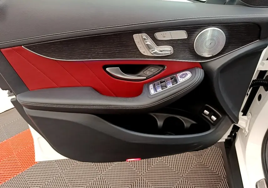 Vue intérieure côté gauche de la porte avant blanche du Mercedes GLC 300 e AMG Line avec garniture cuir rouge et bois.
