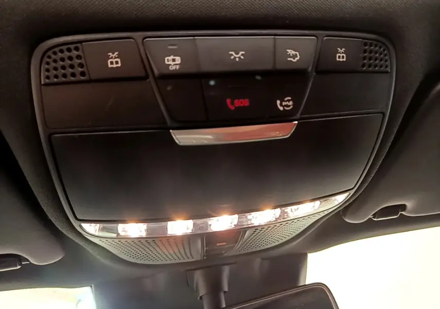 Vue en gros plan du plafonnier intérieur avec commandes d’éclairage et bouton SOS du Mercedes GLC 300 e AMG Line blanc.