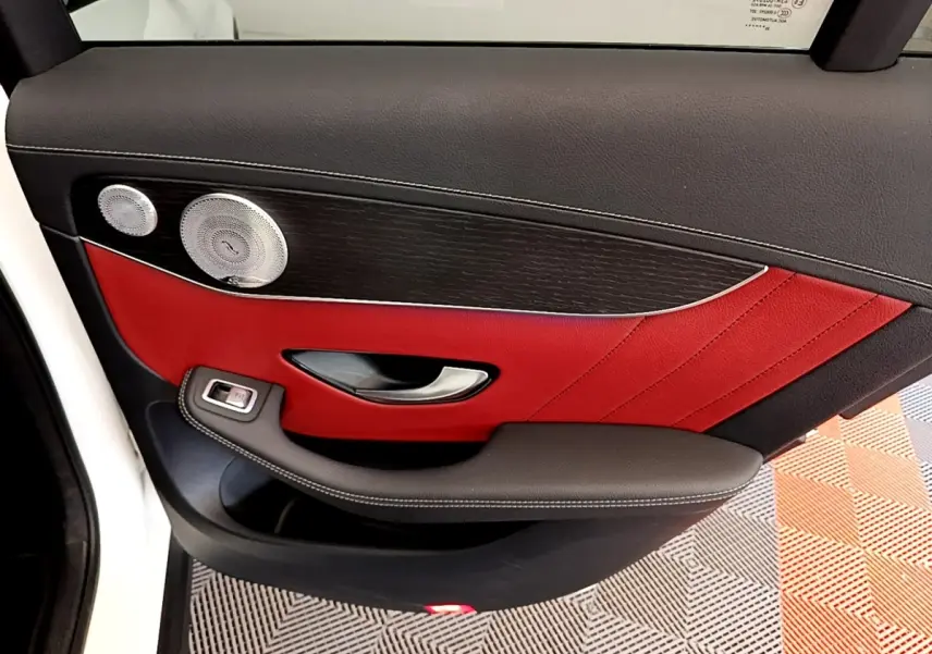 Vue rapprochée de la porte arrière gauche du Mercedes GLC Coupé blanc avec garniture cuir rouge et haut-parleur argenté.