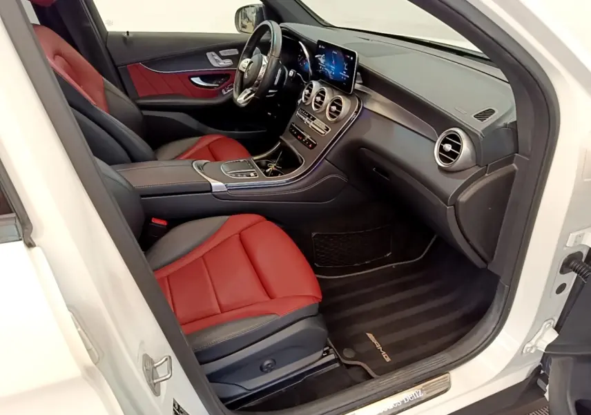 Vue intérieure côté conducteur du Mercedes GLC 300 e AMG Line blanc avec sièges cuir rouge et tableau de bord moderne.