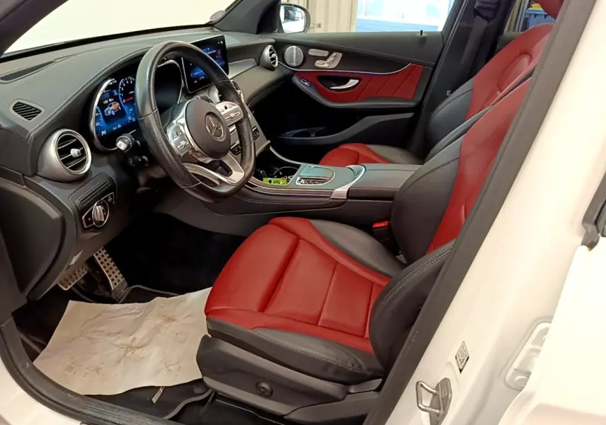 Vue intérieure côté conducteur du Mercedes GLC Coupé blanc de 2020, sièges cuir rouge et noir avec tableau de bord digital.