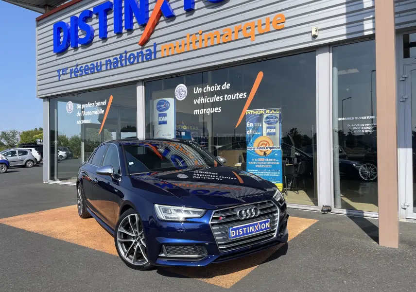 Audi S4 bleu Navarre vue 3/4 avant droit devant un showroom Distinxion, avec calandre et jantes distinctives.