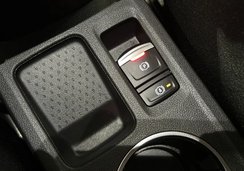 Gros plan sur la console centrale noire du Renault Captur 2024 montrant les commandes du frein à main électrique et auto-hold.