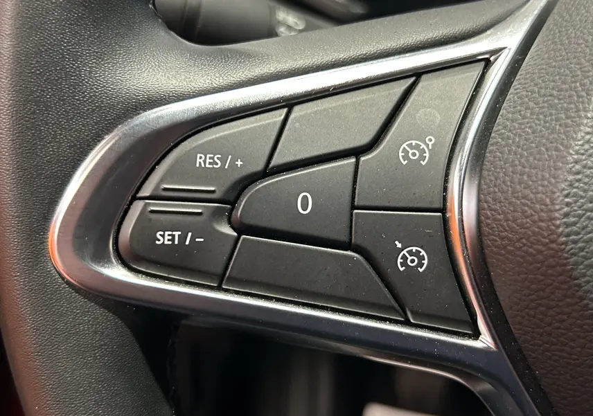 Gros plan sur les commandes de régulateur de vitesse au volant du Renault Captur rouge flamme métal 2024.