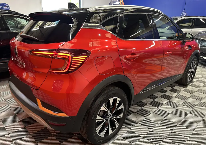 Vue 3/4 arrière droite d'un Renault Captur 2024 rouge flamme métal avec toit noir et feux LED distinctifs.