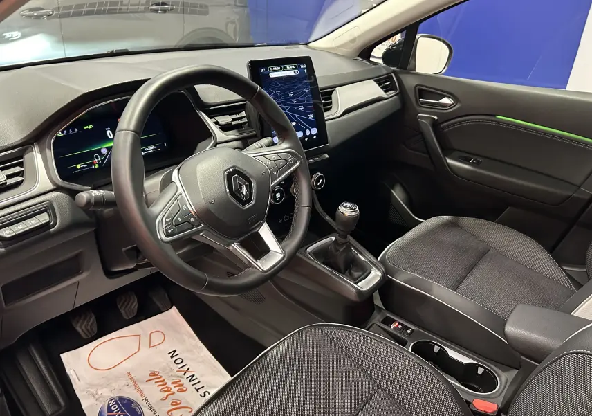 Intérieur de Renault Captur 2024 vu côté conducteur, tableau de bord moderne avec écran tactile vertical et volant multifonction noir.