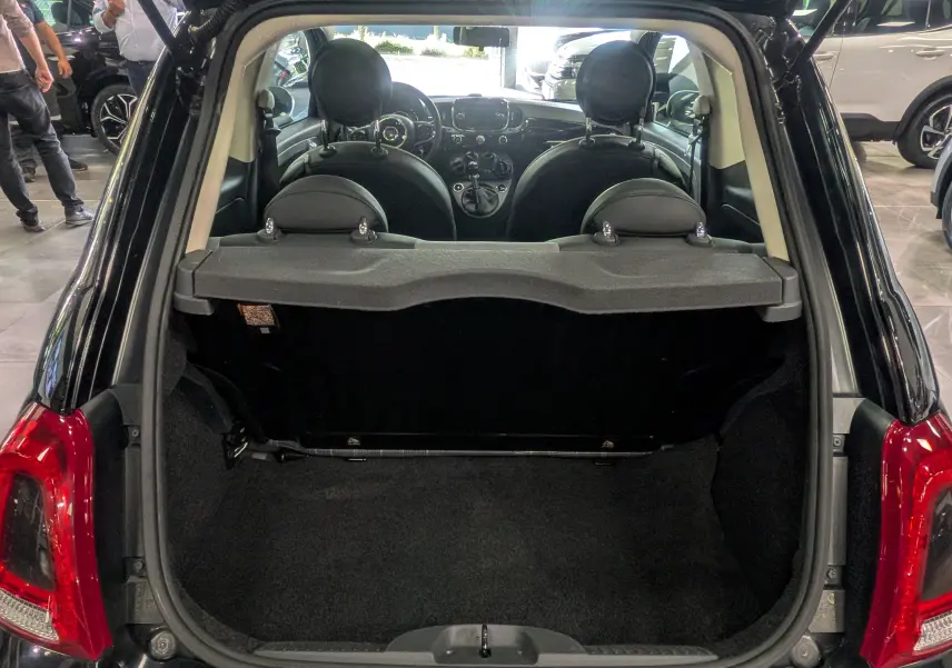 Coffre ouvert vu de l'arrière d'une Fiat 500 noire Crossover Black, intérieur et tableau de bord visibles.