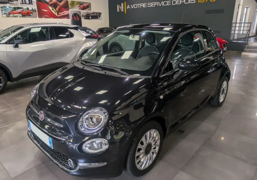 Vue 3/4 avant d'une Fiat 500 noire Crossover Black avec jantes alliage et intérieur cuir noir en showroom.