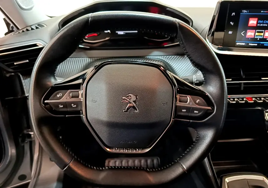 Volant cuir noir Peugeot 2008 2020 vu de face avec commandes intégrées et tableau de bord numérique en arrière-plan.