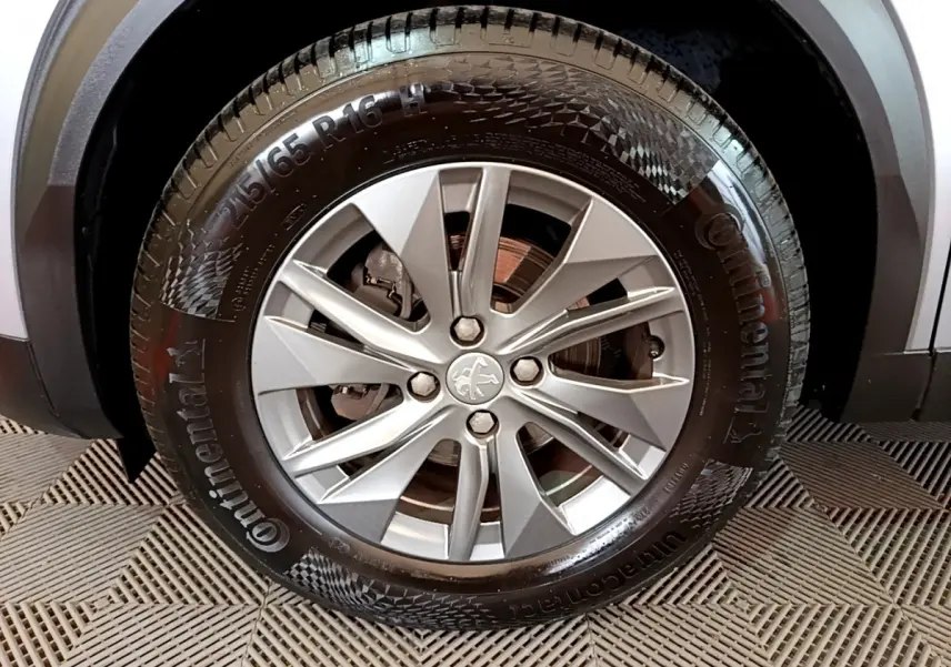 Gros plan sur la roue avant droite du Peugeot 2008 gris clair, mettant en valeur la jante alliage et le pneu Continental.