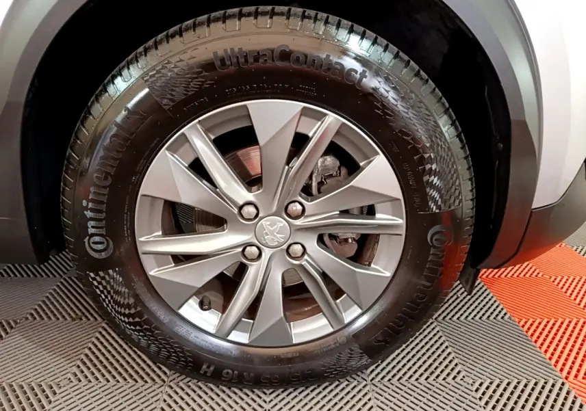 Gros plan sur la roue avant droite d’un Peugeot 2008 gris clair, avec jante alliage et pneu Continental.