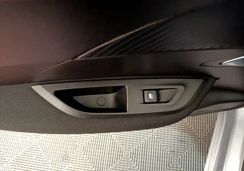Gros plan sur la commande de lève-vitre côté droit de la porte d'une Peugeot 2008 gris clair de 2020.
