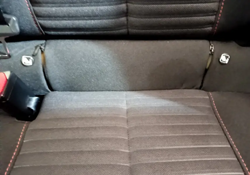 Gros plan sur la banquette arrière noire avec surpiqûres rouges et fixations Isofix du Peugeot 2008 gris clair.