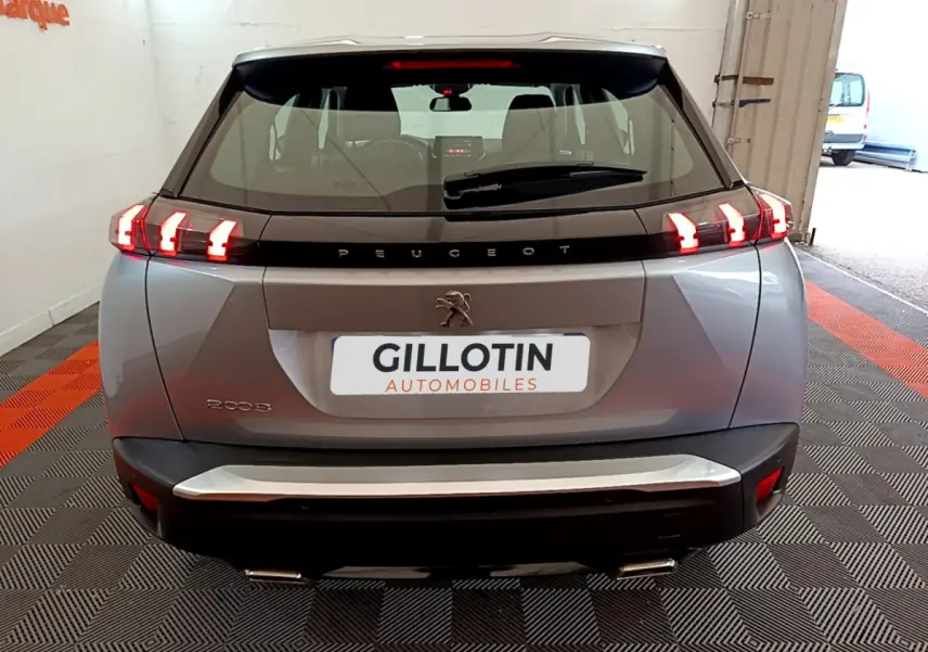 Vue arrière d'une Peugeot 2008 gris clair de 2020 avec feux LED allumés et logo lion visible.