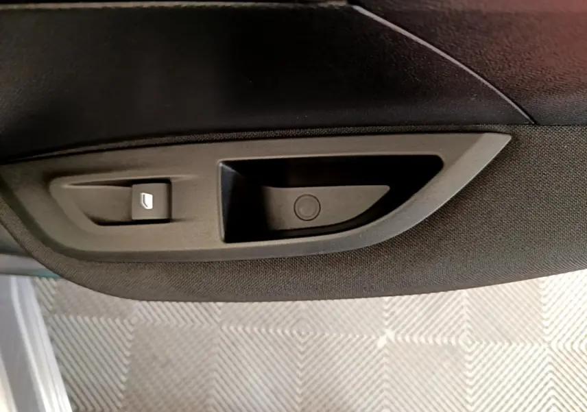 Gros plan sur la poignée intérieure noire de la porte côté conducteur du Peugeot 2008 gris clair 2020.