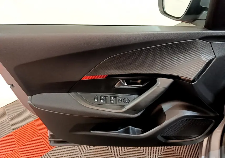Intérieur côté gauche de la porte PEUGEOT 2008 gris clair, avec commandes vitres et insert décor carbone.