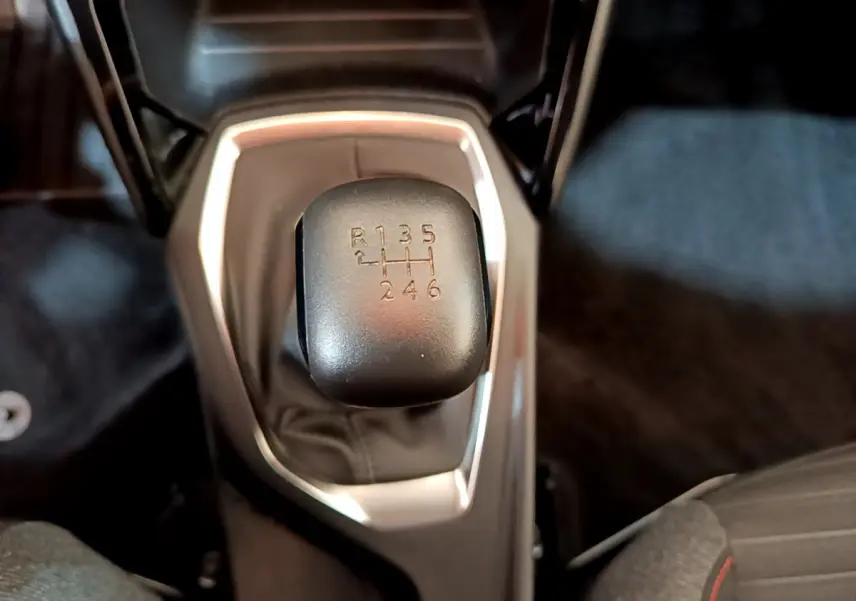 Le levier de vitesses manuel noir de la Peugeot 2008 essence 2020 vu de dessus avec console grise autour.