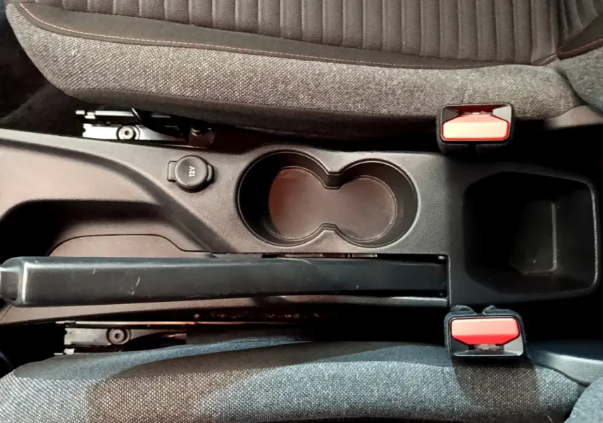 Vue plongeante sur la console centrale du Peugeot 2008 gris clair, avec frein à main et prises 12V visibles.