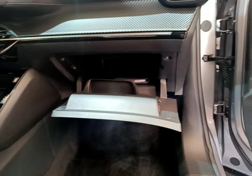 Vue intérieure côté passager du Peugeot 2008 gris clair 2020, boîte à gants ouverte sous tableau de bord noir.
