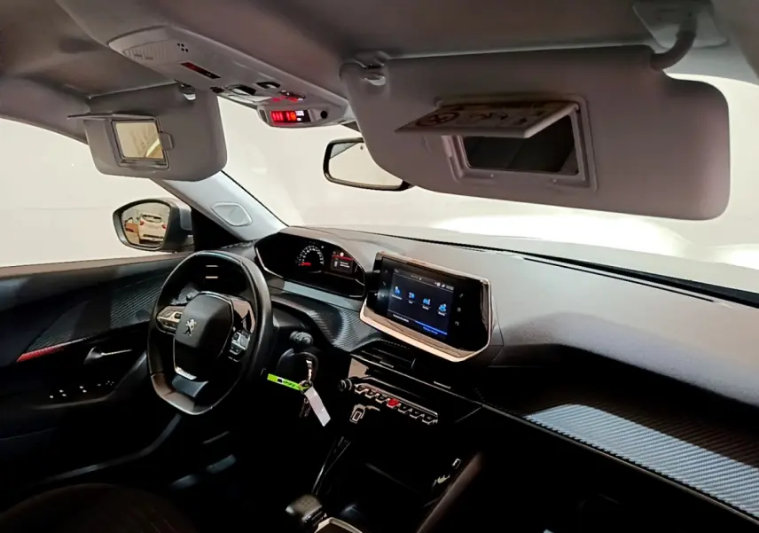 Vue intérieure côté conducteur du tableau de bord et volant cuir noir du Peugeot 2008 gris clair 2020 avec écran tactile central.