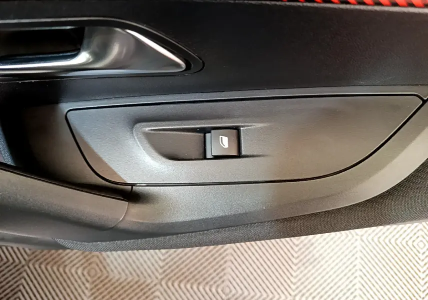 Bouton de commande de vitre électrique sur la porte côté gauche d'un Peugeot 2008 gris clair, intérieur noir.