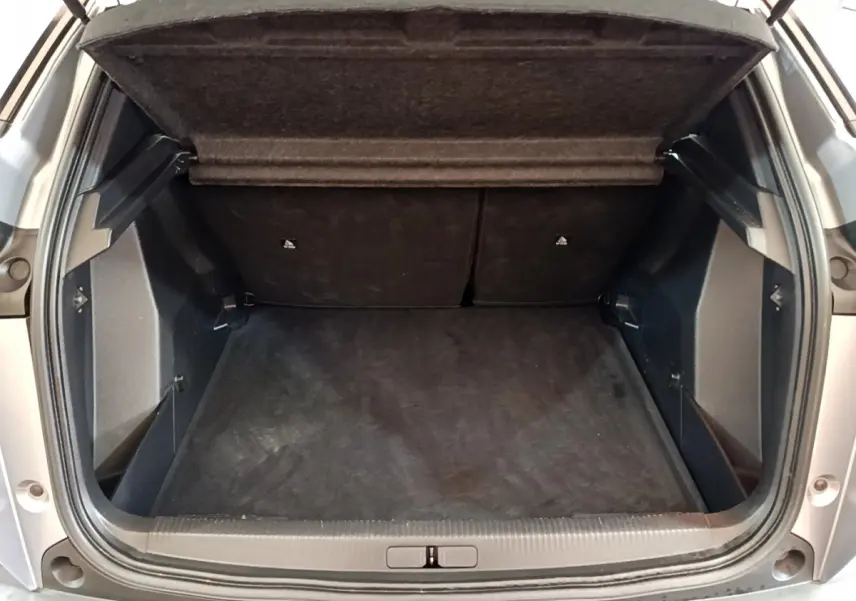 Coffre ouvert d'un Peugeot 2008 gris clair, vue arrière montrant l'espace de chargement et la tablette de séparation.