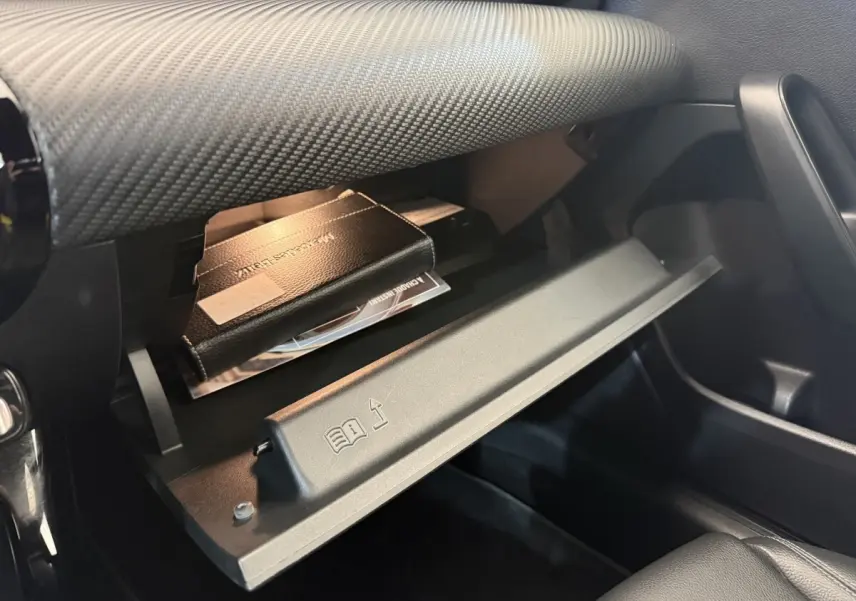 Gros plan sur la boîte à gants ouverte côté passager de la Mercedes Classe A 180 d Business Line, intérieur noir.
