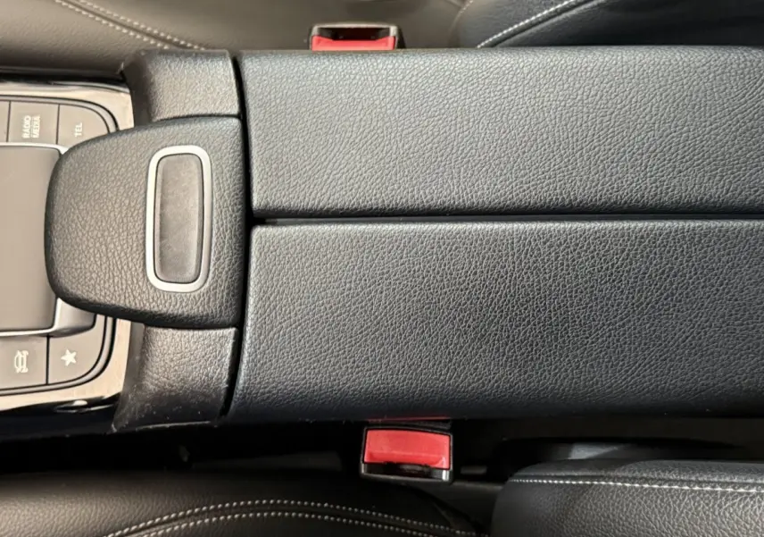Détail de l'accoudoir central en cuir noir avec bouton de frein à main électrique dans une Mercedes Classe A 180 d Business Line.
