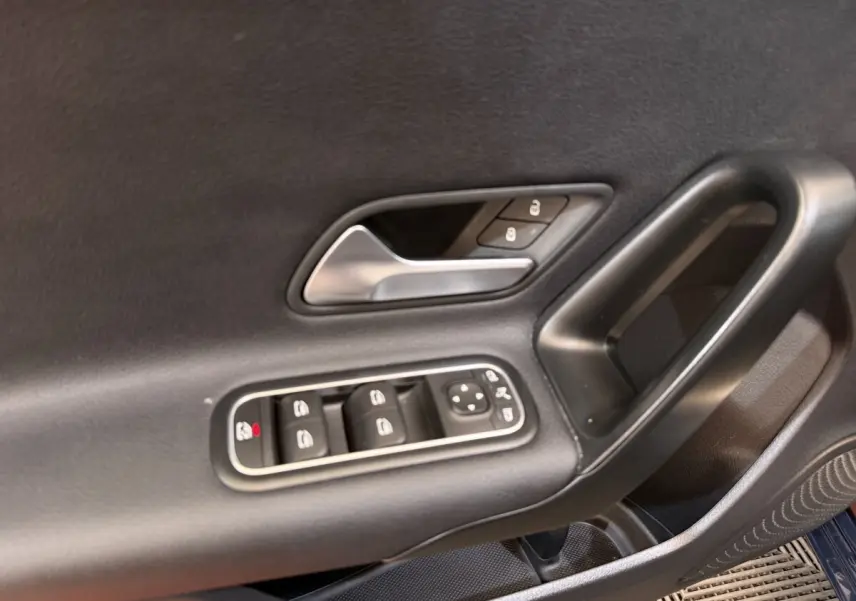 Gros plan sur la porte côté conducteur de la Mercedes Classe A 180 d Business Line bleu, montrant les commandes des vitres et serrures.