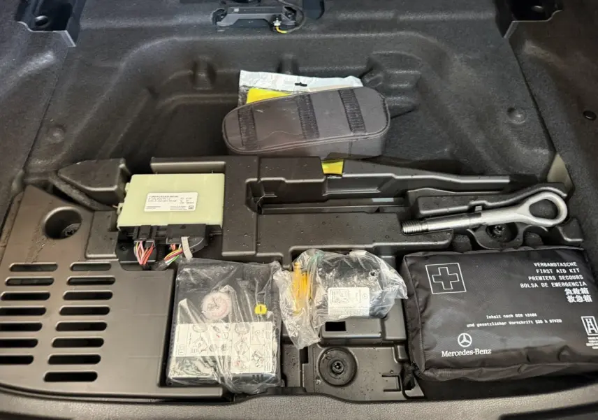 Vue rapprochée du compartiment sous coffre d’une Mercedes Classe A 180 d Business Line 2021, avec trousse de secours et outils.