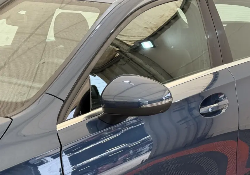 Vue rapprochée du côté gauche d’une Mercedes Classe A 180 d Business Line bleu avec rétroviseur et poignée de porte visibles.