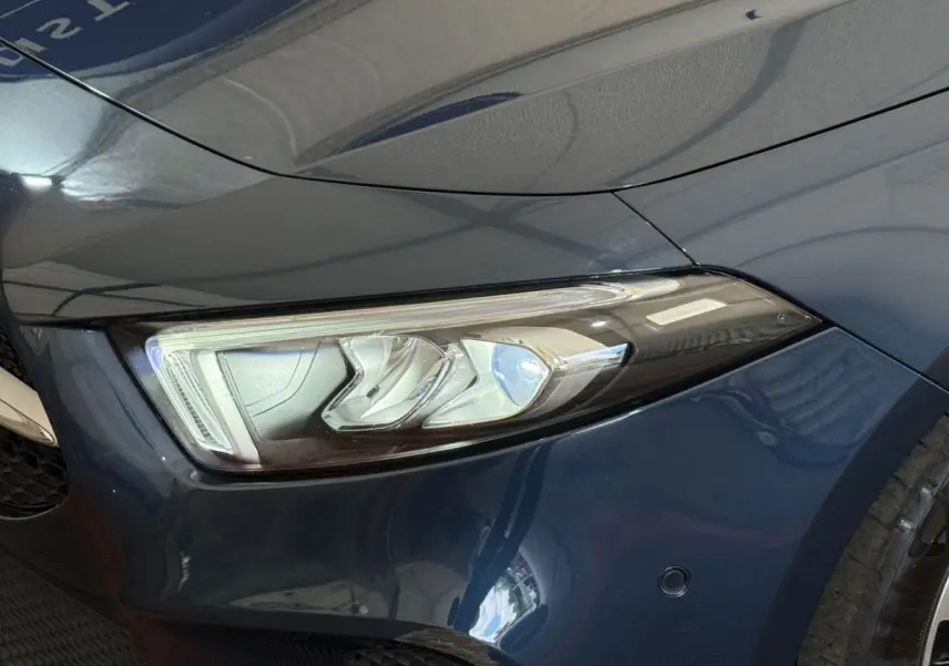 Gros plan sur le phare avant droit LED d'une Mercedes Classe A 180 d Business Line bleu métallisé.