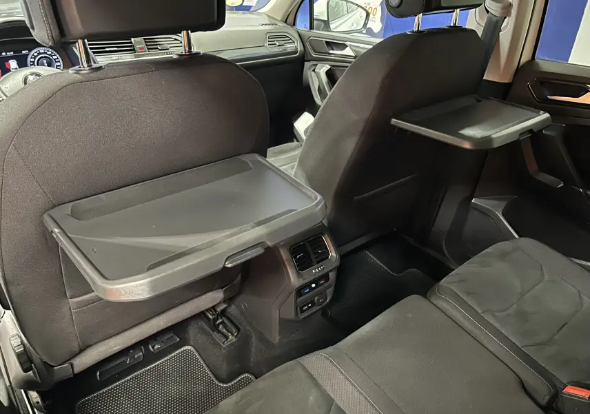 Vue intérieure arrière du Volkswagen Tiguan Allspace 2018 avec tablettes rabattables sur les dossiers des sièges avant.