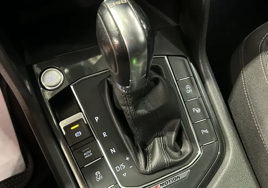 Le levier de vitesses DSG et les commandes autour dans l'habitacle noir du Volkswagen Tiguan Allspace blanc.