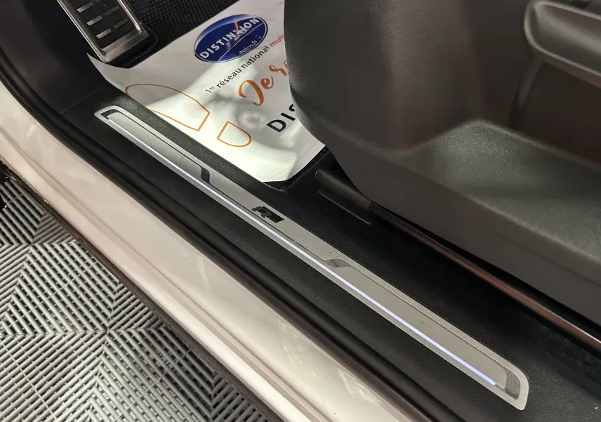 Gros plan sur la plaque de seuil de porte avant droite blanche du Volkswagen Tiguan Allspace avec logo R rétroéclairé.