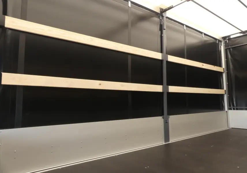 Vue intérieure du Renault Master Extra 2025 gris, montrant la bâche noire avec renforts en bois et plancher foncé.