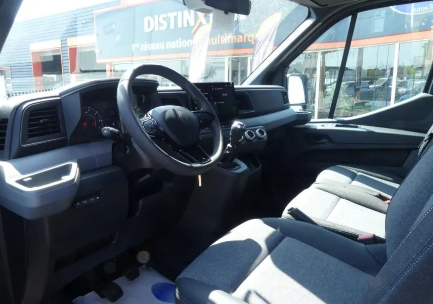 Intérieur du Renault Master Extra 2025 vu côté conducteur, volant multifonction et sièges tissu gris chiné visibles.