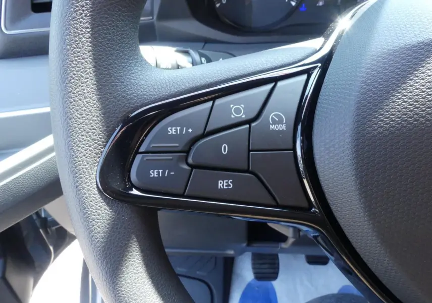 Gros plan sur les commandes du volant noir du Renault Master Extra gris, côté gauche du poste de conduite.