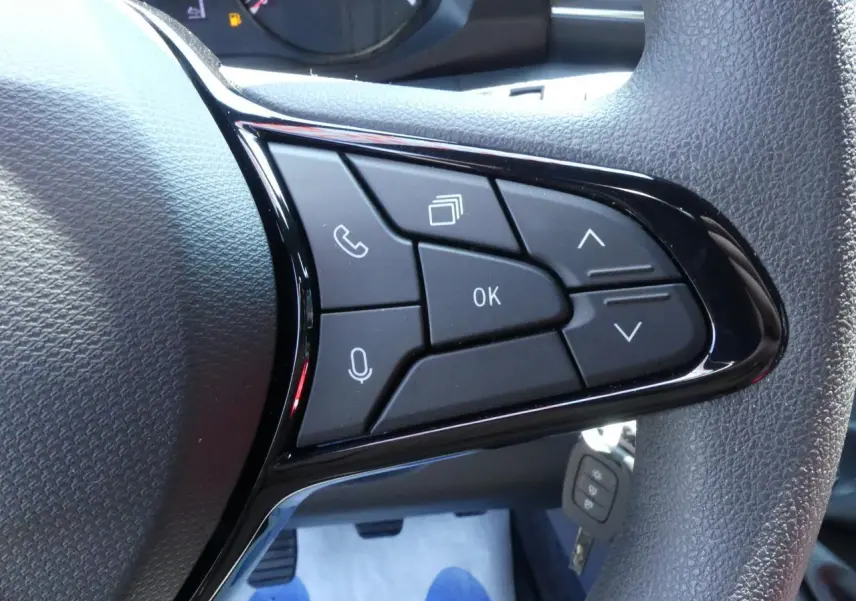 Gros plan sur les commandes multifonctions noires du volant du Renault Master Extra 2025, finition tissu gris.