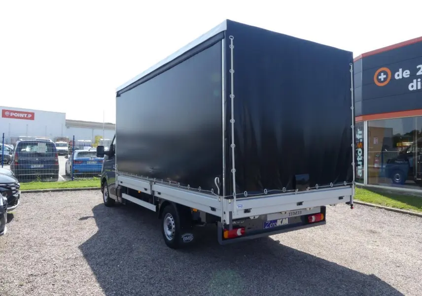 Renault Master Extra gris vu en 3/4 arrière droit avec bâche noire et jantes tôles 16 pouces.