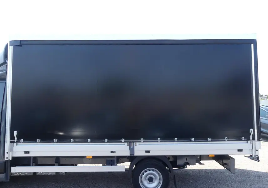 Profil latéral droit du Renault Master Extra 2025 gris avec bâche noire couvrant la zone de chargement.