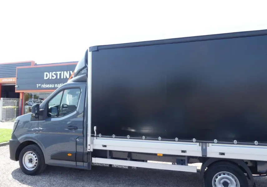 Vue de profil côté gauche d'un Renault Master Extra gris avec bâche noire et jantes tôles 16 pouces.