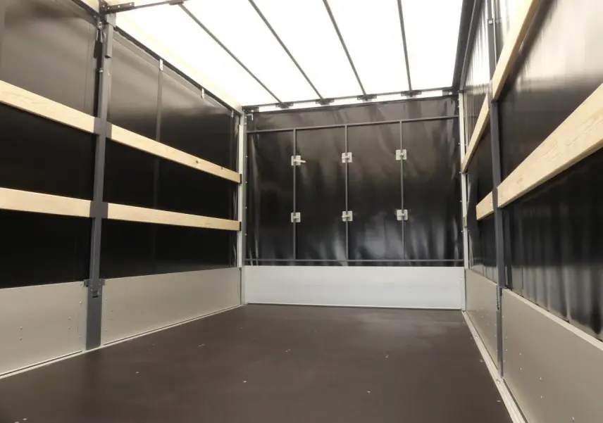 Intérieur de la bâche noire du Renault Master Extra 2025, montrant les parois latérales et arrière avec renforts bois.
