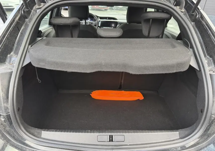 Coffre ouvert d'une Opel Corsa noire vue de l'arrière avec cache-bagages et triangle de sécurité orange.