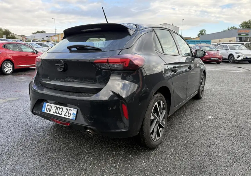 Opel Corsa noire vue 3/4 arrière droit, avec jantes alliage 16 pouces et spoiler arrière sportif.