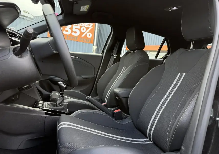 Intérieur noir de l'Opel Corsa 2024, vue côté droit sur sièges sport avec surpiqûres blanches et volant multifonction.