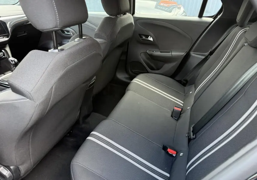 Vue intérieure arrière côté droit de l'Opel Corsa 2024 noire, banquette tissu noir à bandes blanches et appuie-têtes réglables.